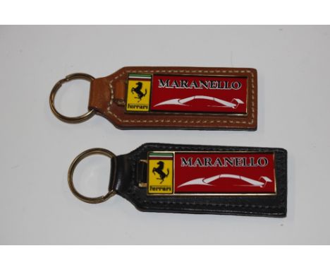 A pair of unusual enamel and leather backed Maranello Feerrari key fobs