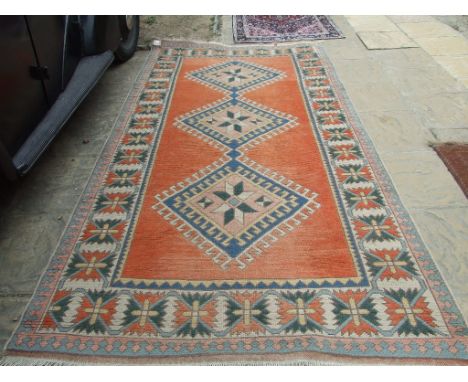 A Turkish carpet, decorated three central lozenges on a light red ground, within a multi border, 294 x 159 cm