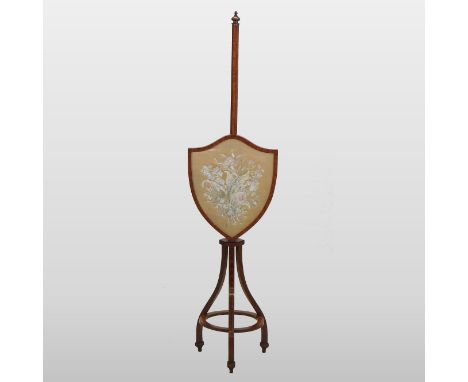 A 19th century Sheraton style satinwood pole screen, the adjustable shield shaped panel inset with a floral silkwork, the tri