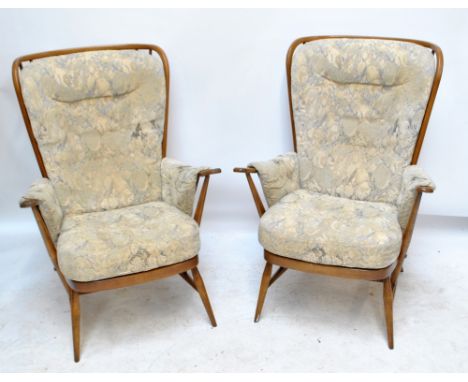 ERCOL; a pair of stick back upholstered armchairs raised on outsplayed turned legs. CONDITION REPORT: Some wear to the frame 