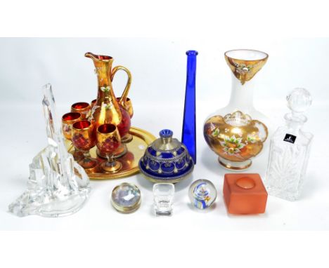 A small collection of glassware including a red and gilt tot set, a Royal Doulton cut glass decanter, and a white and gilt va