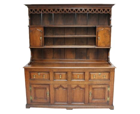 An 18th century oak dresser, with moulded and pierced cornice above boarded plate rack with two cupboard doors, the cupboard 
