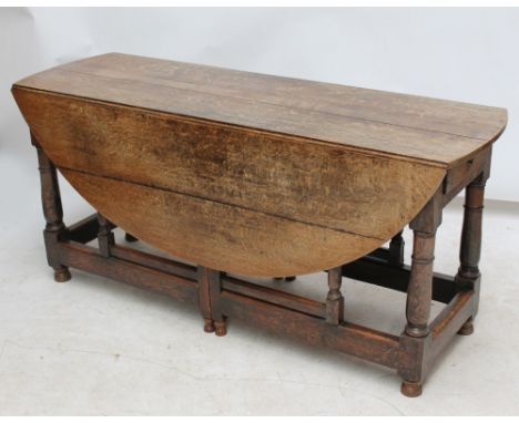 An 18th century oak gateleg table with opposing frieze drawers and turned supports united by stretchers, length 161cm. CONDIT