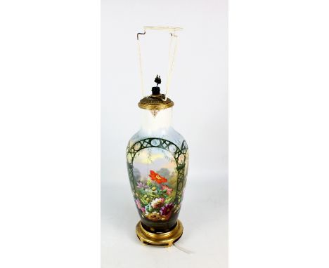 A late 19th/early 20th century porcelain lamp base of baluster form overall painted with floral motifs with garden background