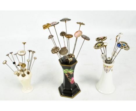 A collection of hat pins including mother of pearl examples, circular white metal and crystal examples in three ceramic hat p