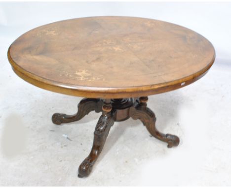 A late 19th century oval walnut loo table with inlaid motifs, four turned supports united with a finial to carved cabriole le