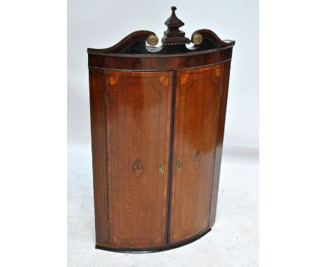 A late George III oak and mahogany crossbanded bowfronted wall corner cupboard with broken swan neck pediment above pair of i