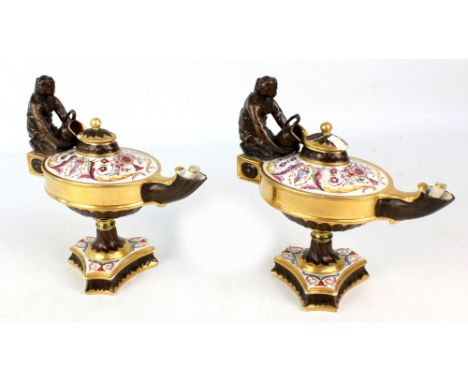 A pair of French porcelain table oil lamps modelled as a footed Roman lamp on tripartite base painted with floral and foliate