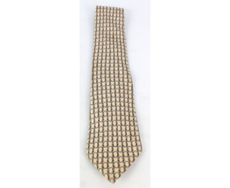 HERMÈS; a silk tie decorated with loop motifs on beige ground.