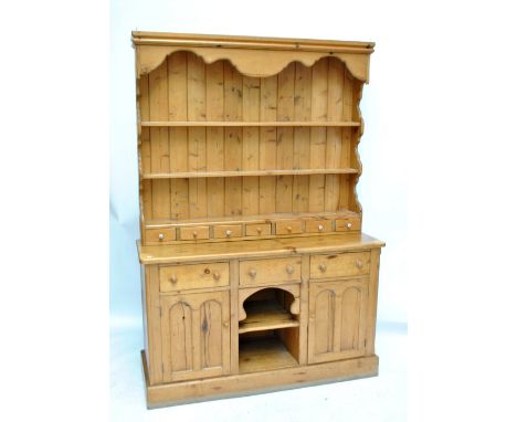 A Victorian pine dresser with boarded rack with three shelves above seven small drawers (some with ceramic handles), the base