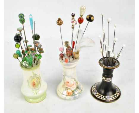 A collection of hat pins including a number of white globular glass headed examples, a green collection including enamelled p