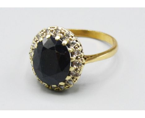 A 9ct Gold Sapphire And Diamond Cluster Ring, the large oval sapphire surrounded by diamonds within a pierced setting, 4.2 gr