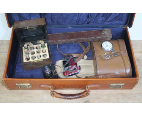 A vintage case of assorted items including a Triumph car badge, chemist's bottles in wooden case, binoculars, an Ingersoll Tr