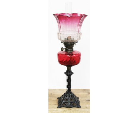 A Victorian cast iron oil lamp with ruby glass reservoir and etched cranberry glass shade, height 68cm (including flue).  Con