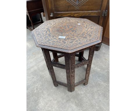 AN OCTAGONAL HEAVILY CARVED COFFEE TABLE ON FOLDING BASE BEARING LABEL M 