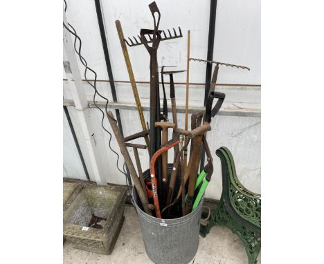 A GALVANISED DUST BIN WITH AN ASSORTMENT OF GARDEN TOOLS TO INCLUDE RAKES AND HOES ETC 
