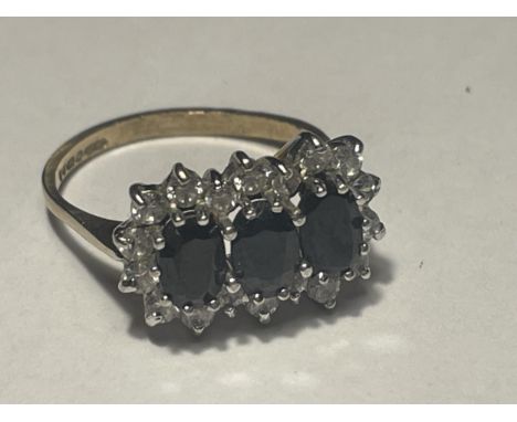 A 9 CARAT GOLD RING WITH THREE LARGE IN LINE SAPPHIRES SURROUNDED BY CUBIC ZIRCONIAS SIZE L/M 