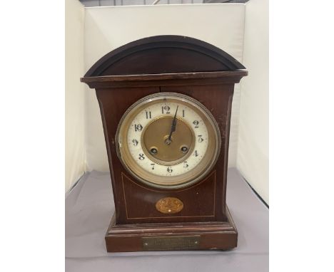 A MAHOGANY INLAID MANTLE CLOCK WITH INSCRIPTION PLATE (A/F LEG MISSING) 