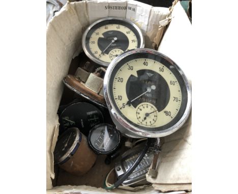 A box containing vintage car speedometers and other dials 
