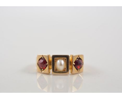 An 18 carat yellow gold dress ring with a pearl to the centre and garnet to each side claw and gypsy set in individual square