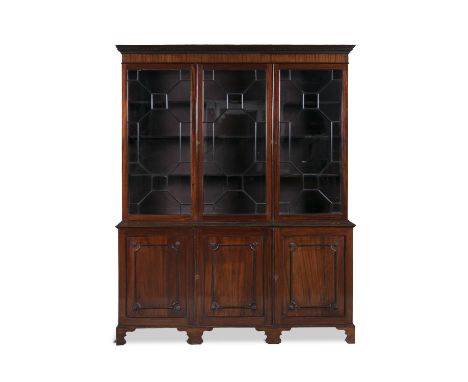 A 19TH CENTURY MAHOGANY TRIPLE DOOR BOOKCASE, with moulded dentil cornice above astragal glazed panel doors, on a cupboard ba