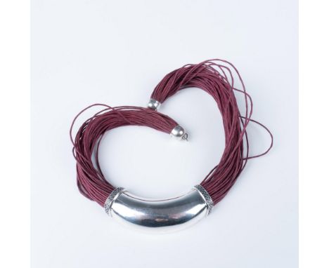 A curved thick sterling silver pendant on joined crimson colored chords. The pendant has a diamond shaped pattern on two side