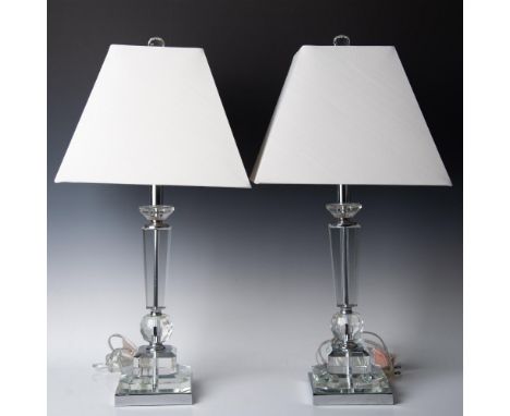 A pair of clear crystal table lamps that have square bodies and bases, adorned with a crystal ball and diamond-shaped pieces,