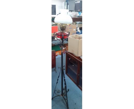 A 20th Century standard oil lamp with wrought iron base and red glass shade. Location:LWM 