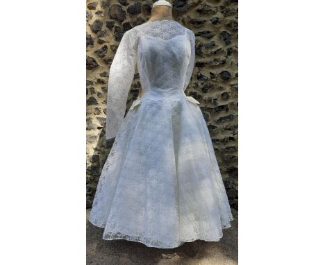 A 1960's Palmers of Watford white lace wedding dress with satin bows to the waistband, 24"Wx32"C together with original depar