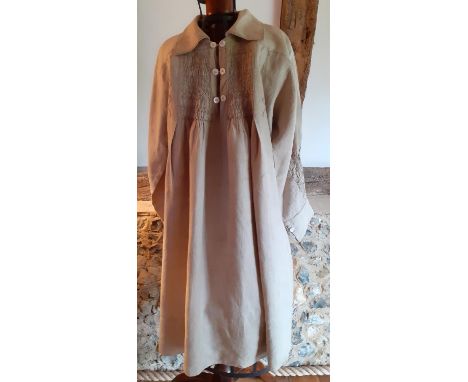 A 19th Century pale brown farmer's linen smock with embroidered detail to the front, back and sleeves having 6 mother of pear