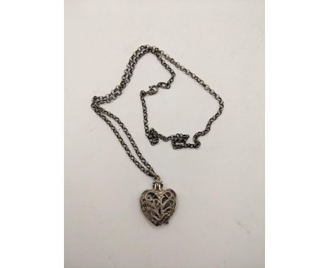A silver pendant fashioned as a heart opening to reveal a ring, with pierced, scrolled ornament on a necklace, Location:CAB1 
