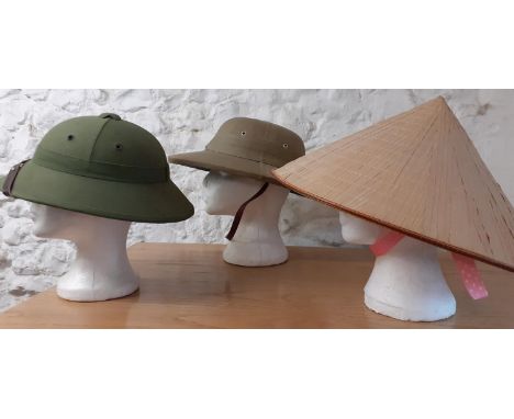 A Vietnam style green pith helmet together with a 1986 Raffles Hotel 100th Anniversary light khaki pith helmet manufactured b