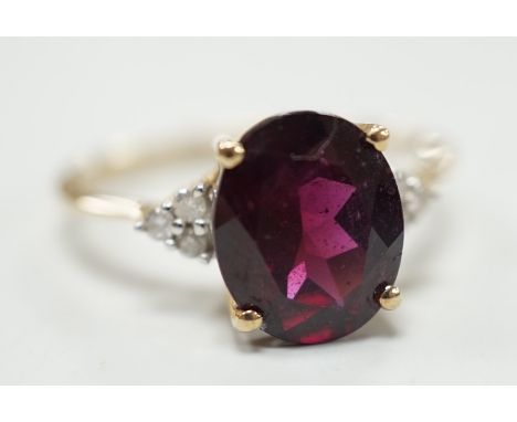 A modern 9ct gold, single stone oval cut garnet and six stone diamond chip set dress ring, size R/S, gross weight 2.8 grams.