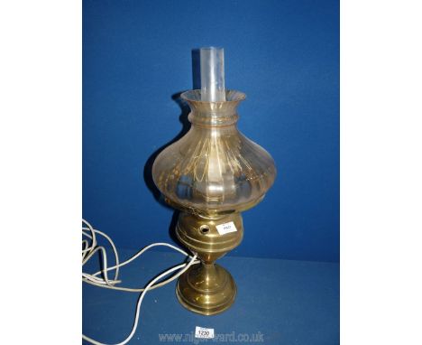 An Oil Lamp converted to electric with a brass base with a tinted orange shade and clear chimney, a/f, 21" tall.