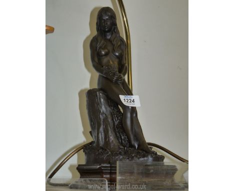A lamp base with figure of a lady holding flowers, on a wooden base, with shade.