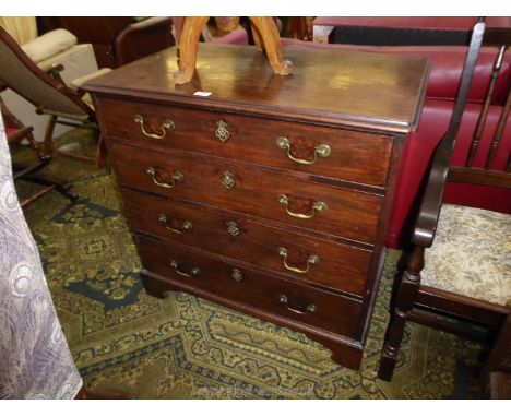 A compact Oak carcassed Georgian Mahogany Chest of four long Drawers standing on bracket feet, with brass swan neck drop hand