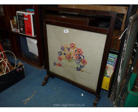 A dark wood framed tapestry fire screen depicting flowers, 29" tall.