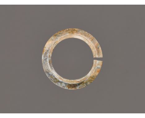 A JADE COLLARED SLIT-RING, SHANG DYNASTYChina, 1600 to 1046 BC. Of circular form, the jade is pierced with a wide collared ap