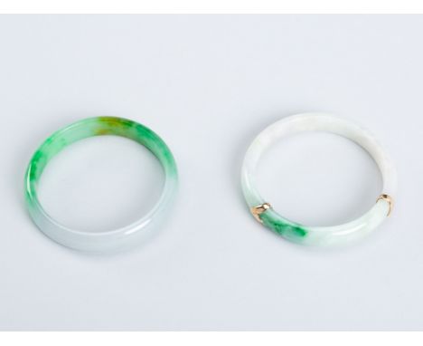 A GROUP OF TWO JADEITE BANGLESChina, mid-20th century. Each of circular form, the polished semi-translucent stones in various