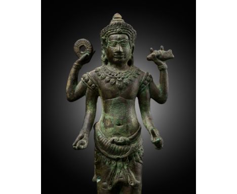 A BRONZE FIGURE OF VISHNU, ANGKOR PERIODKhmer Empire, 13th century. The four-armed deity standing in samabhanga on a circular