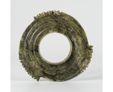 A SERPENTINE COLLARED NOTCHED DISC, ZHOU STYLEChina, 20th century or earlier. Of circular form, the jade is pierced with a wi