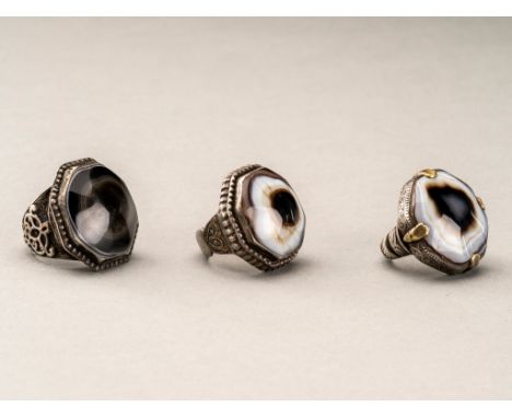 A GROUP OF THREE HIMALAYAN BUDDHA EYE AGATE INSET SILVER RINGSHimalayan region, late 19th century. Each ring inset with a dom