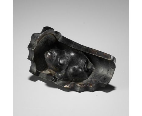 A RARE HORN NETSUKE OF A PUPPY NESTLED WITHIN A ROOF TILE, ATTRIBUTED TO HORAKUAttributed to Horaku, unsignedJapan, Kyoto, ea