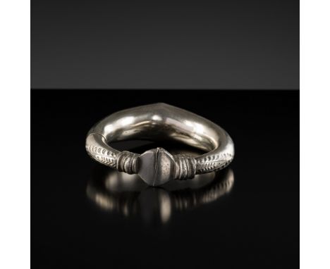 AN INDIAN TRIBAL SILVER BANGLE, c. 1900sRajasthan, India. Of almost circular form, the tubular sides gradually taper towards 