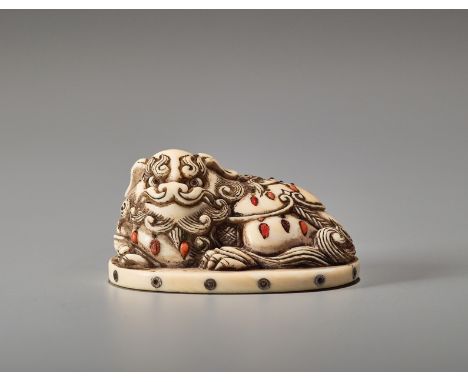 AN INLAID IVORY NETSUKE OF A RECUMBENT SHIBAYAMA SHISHIJapan, late 19th century, Meiji period (1868-1912)The shishi's head sh