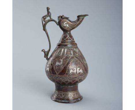 A SILVER AND COPPER-INLAID BRASS EWER, SELJUK STYLEIran, 19th century. Finely cast and engraved, supported on a tall, flaring