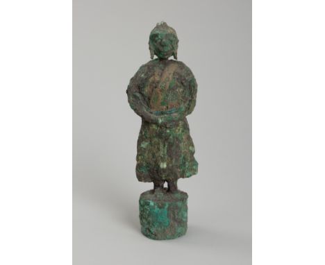 A BRONZE FIGURE OF A MAN, DONG SON CULTUREVietnam, 500 BC to 300 AD. Modeled as a man standing on a round pedestal, his face 