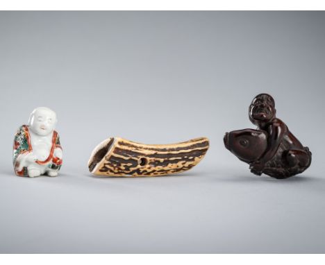 A GROUP OF THREE NETSUKEUnsignedJapan, 19th centuryThe first porcelain netsuke depicting a rotund Hotei seated wearing a fine