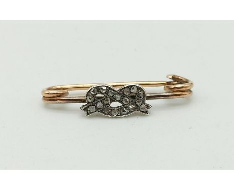 A Vintage Rose-Cut Diamond Knot Brooch. 17 diamonds. Mounted on a yellow metal safety pin. 