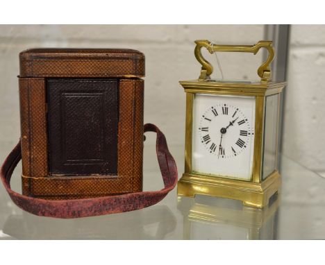 A brass carriage clock with leather carrying case and key.